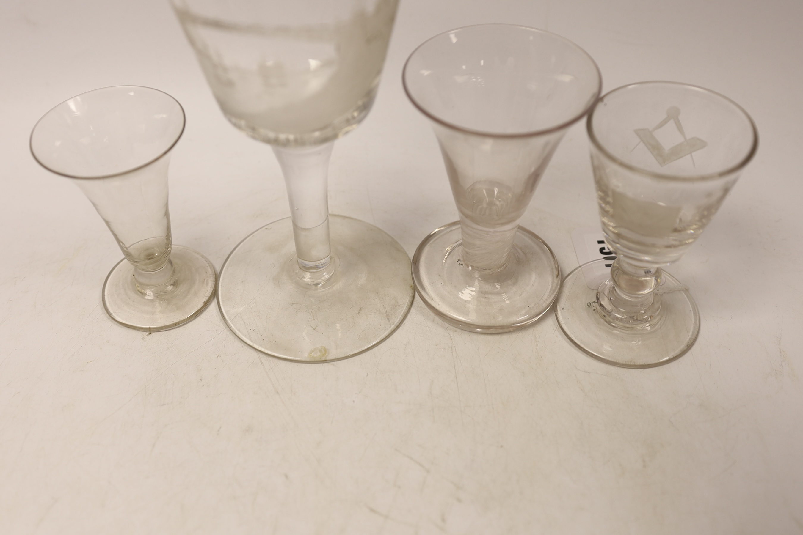 Four late 18th century drinking glasses; a DSOT stem toast masters glass, one with wheel engraved Masonic symbols, and a large wheel engraved goblet decorated with a view of Sunderland bridge, 20cm high